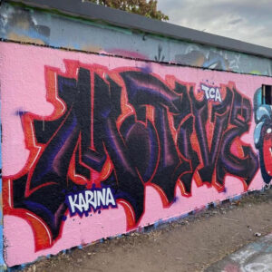 Graffiti in black red and purple on pink wall by motive